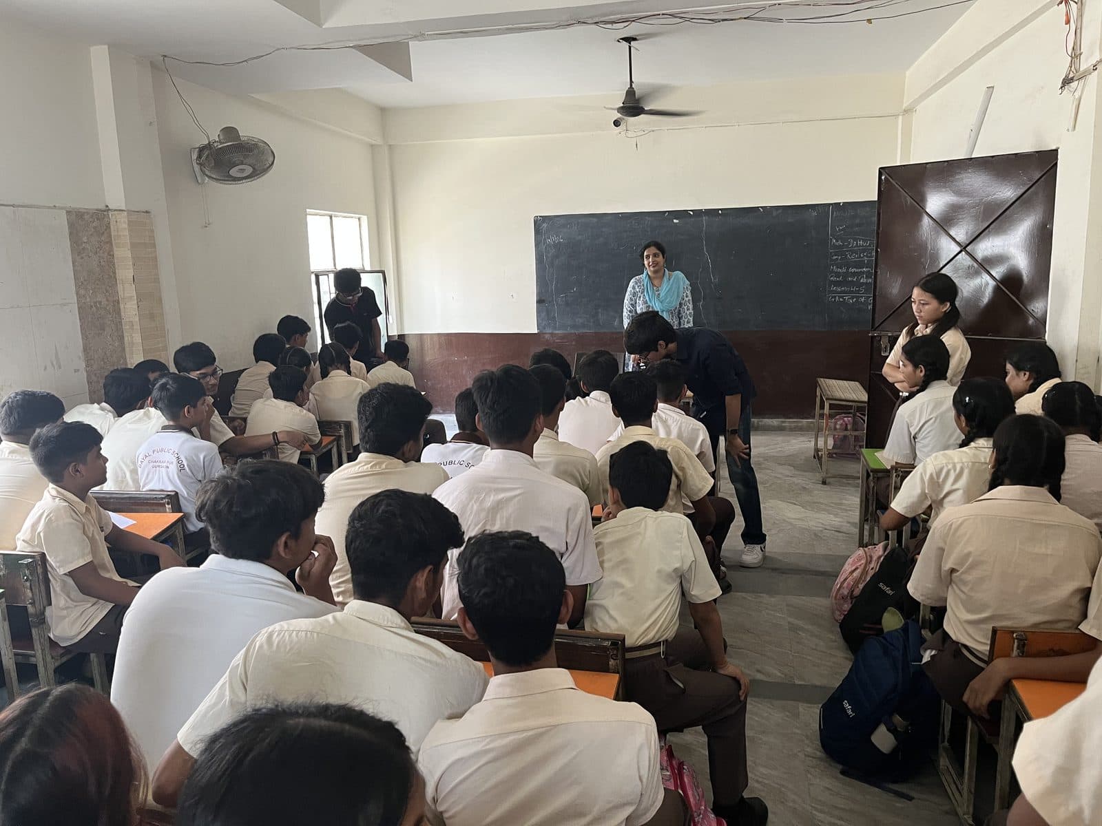 A full classroom at Dayal Public School seen from the back, students at their desks and a teacher at the front.