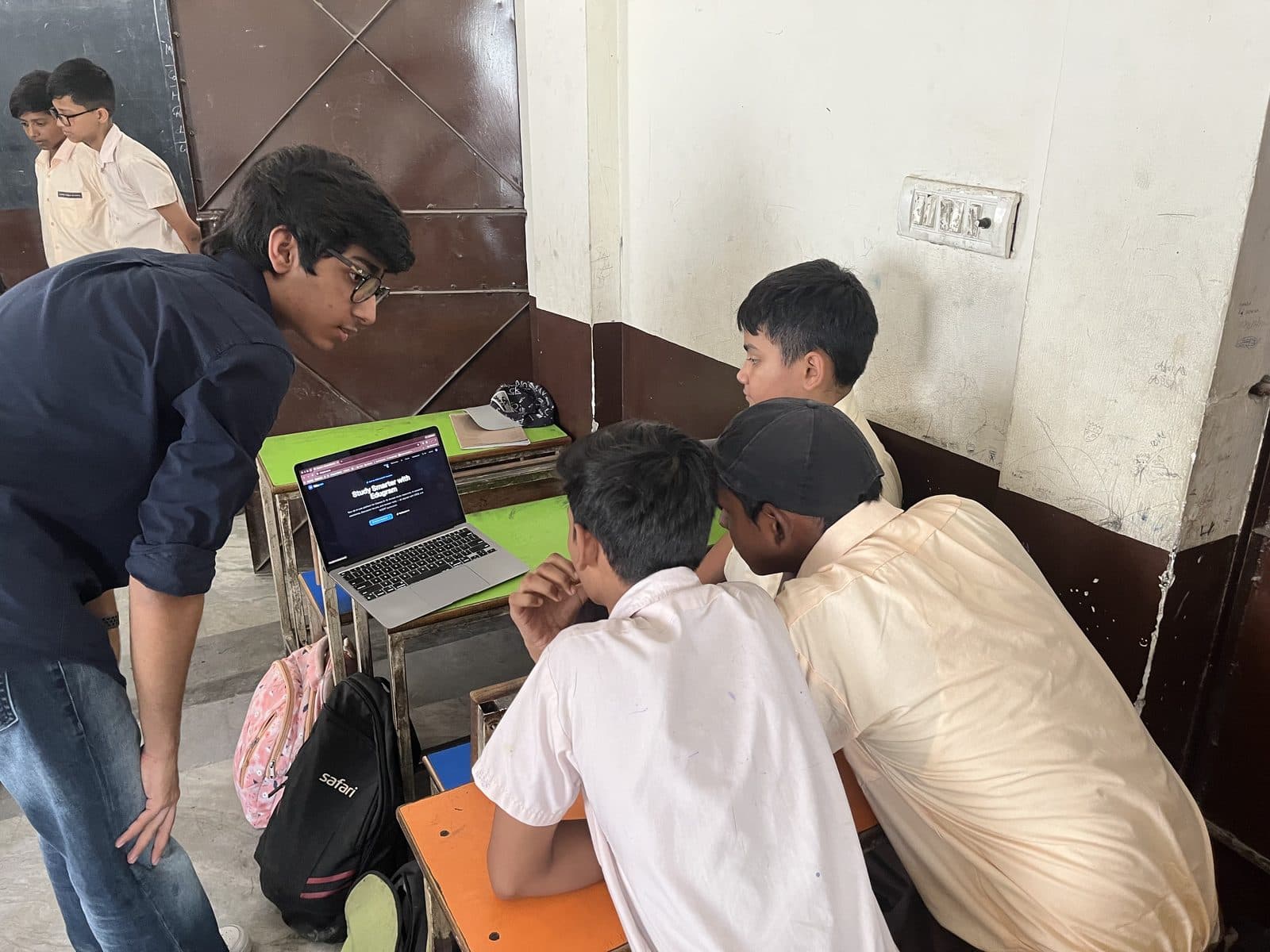 Students gathered around a laptop showing the Edugram site, a member of the Edugram team beside them.