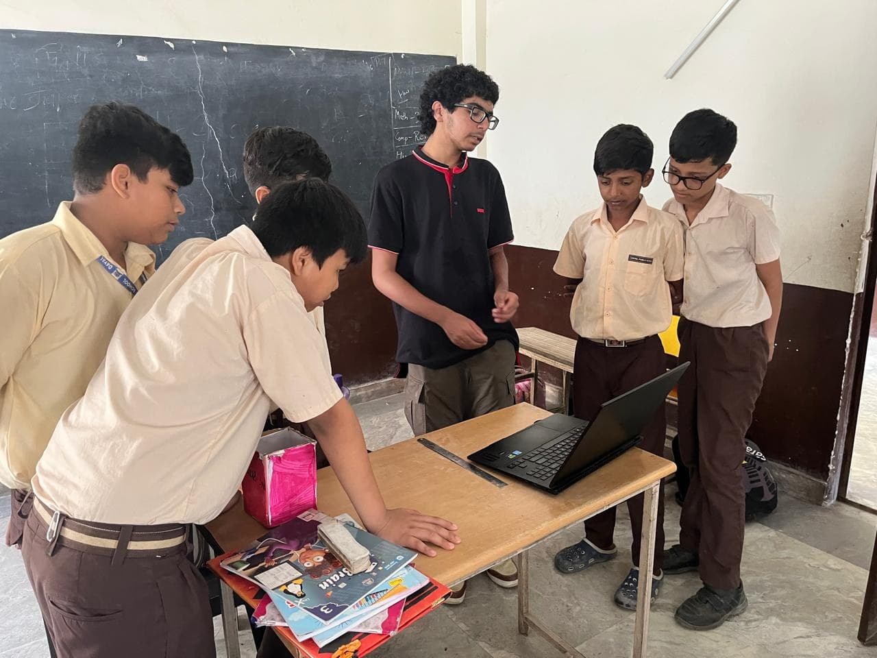 Five students at Dayal Public School gathered around a laptop on a classroom desk while a member of the Edugram team talks them through the site.