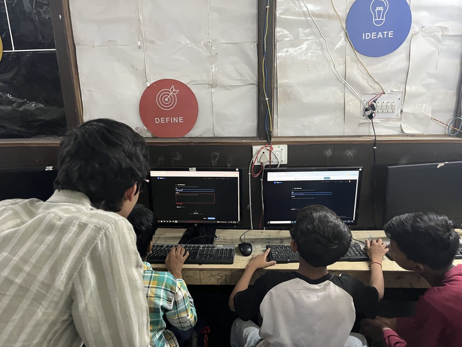 Two students at Prayatna working through the Edugram site on desktop computers, a member of the Edugram team beside them.